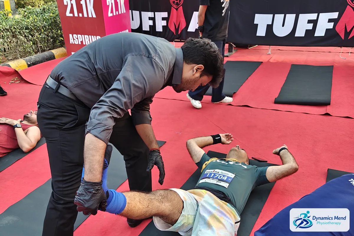 Dynamics Mend physiotherapist giving a runner an assisted hamstring stretch after the Tuffman Gurugram Half Marathon