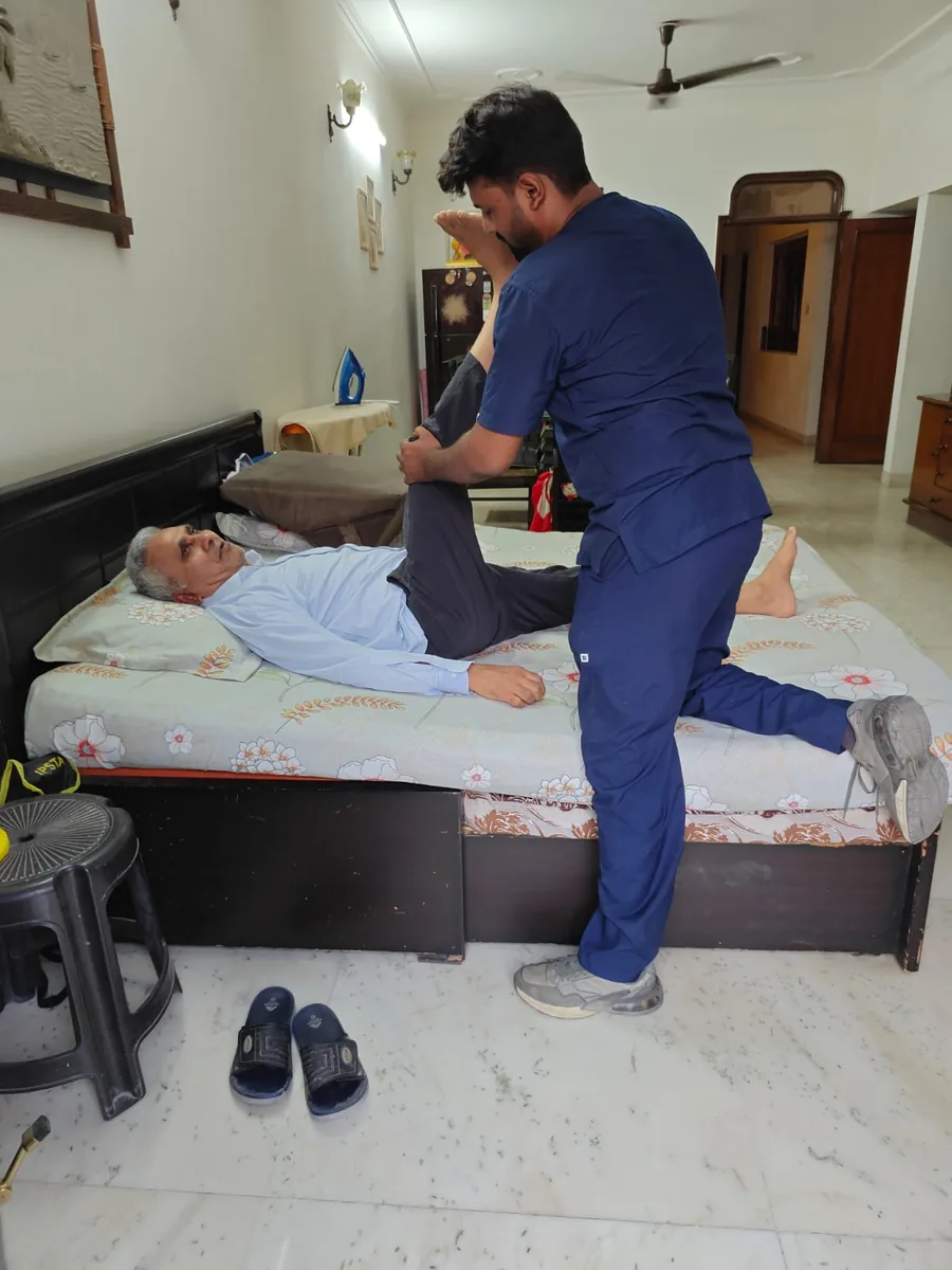 Dynamics Mend physiotherapist doing hip mobilisation for an elderly patient at his home in Noida